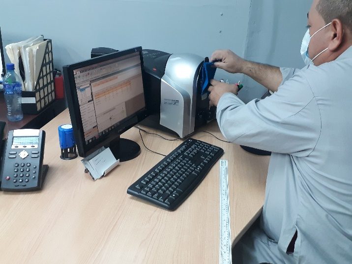 A laboratory technician taking a Datacolor spectrophotometer reading on a fabric swatch.