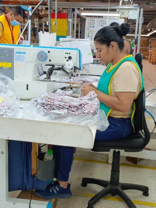 An operator sewing a printed garment at a Jack industrial machine.