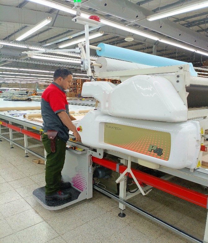 An operator running a Tukatech P4 automated spreader along a cutting table.